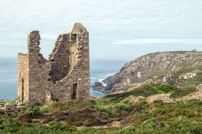 Old ruin building by sea against sky