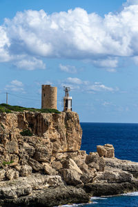 Lighthouse by sea against sky