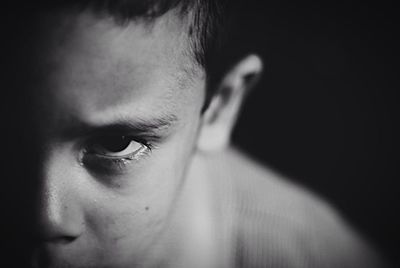 Close-up of serious boy against black background