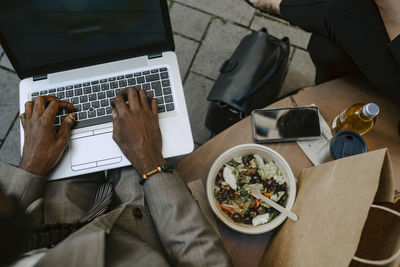 High angle view of businessman's hands working on laptop