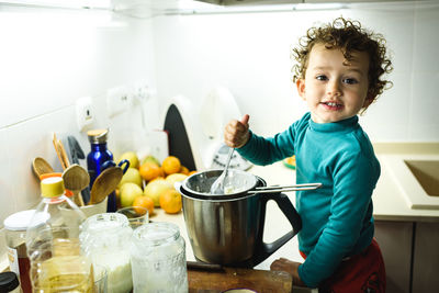 Portrait of smiling girl preparing food at kitchen