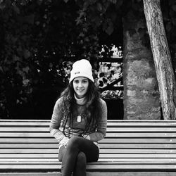 Portrait of smiling young woman sitting against tree