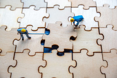 High angle view of figurines picking wooden jigsaw puzzle