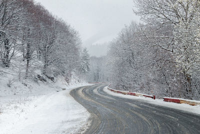 Snow covered road against sky during winter