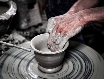 Cropped hands of man molding shape on pottery wheel