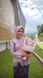 Portrait of smiling woman standing against pink wall