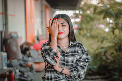 Young woman looking away while standing outdoors