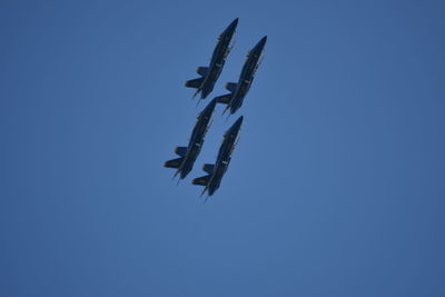 Low angle view of airplane flying against clear blue sky