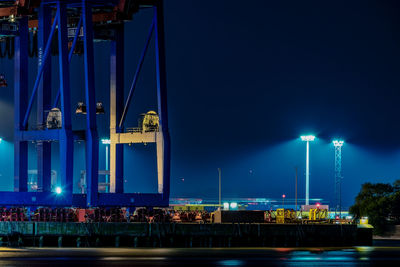 Illuminated pier against blue sky at night