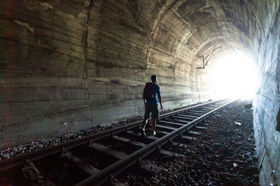 Rear view of man walking in tunnel