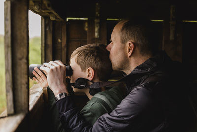 Boy and father birdwatching with binoculars