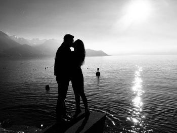 Silhouette men standing on sea against sky