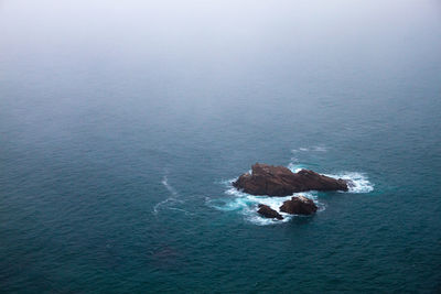 High angle view of rock formation in sea against sky