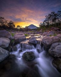 Scenic view of waterfall against sky during sunset