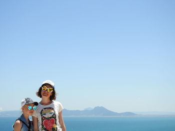 Portrait of woman in sunglasses against clear blue sky