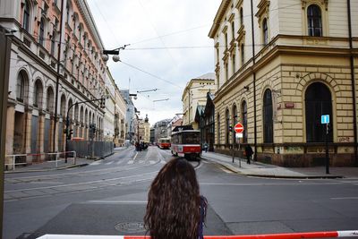Rear view of woman looking at tramway amidst buildings in city