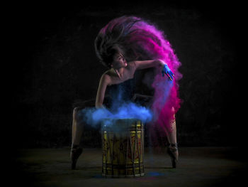 Full length portrait of woman against black background