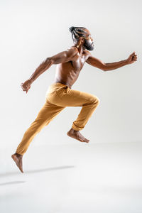 Low section of woman jumping against white background