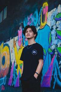 Young man standing against graffiti wall