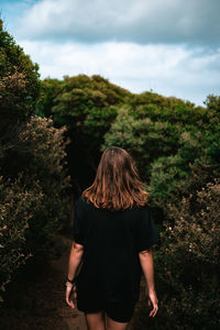 Rear view of woman looking at trees against sky