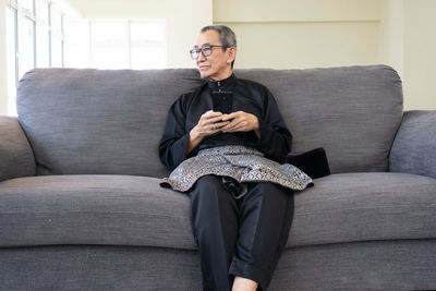 Full length of man sitting on sofa