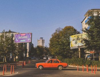 Road sign by trees against clear sky