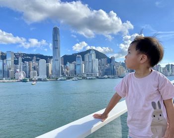 Side view of asian boy standing by sea against sky