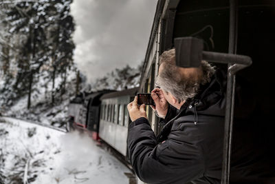 Portrait of man holding camera in winter