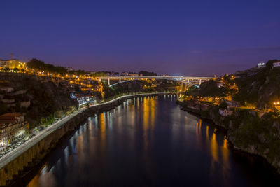 Illuminated bridge over river in city against sky at night