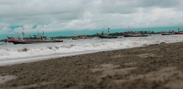 Boats moored on beach against sky