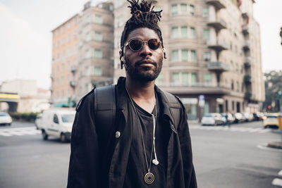 Portrait of young man wearing sunglasses standing on street in city