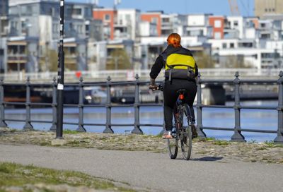 Rear view of man riding bicycle on city