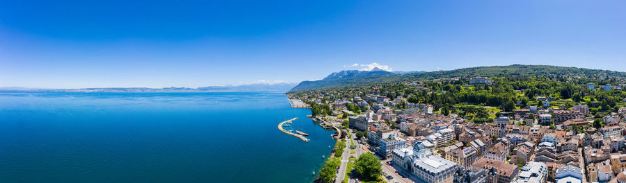High angle view of townscape by sea against clear blue sky