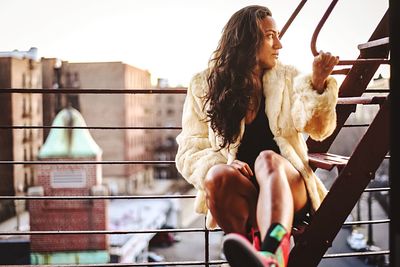 Young woman sitting on railing