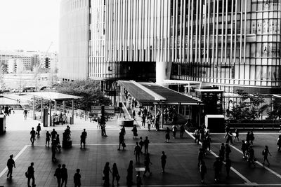 People walking on street against modern buildings in city