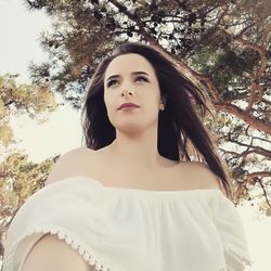 Low angle view of beautiful woman standing against trees