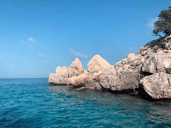 Rocks by sea against blue sky