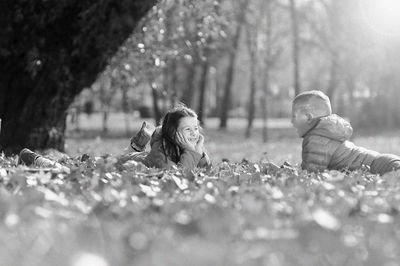 Happy siblings talking while lying on grassy field at park