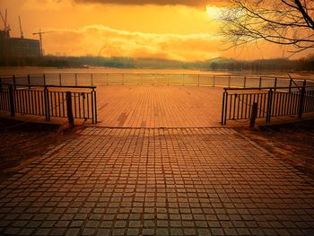 Footpath by sea against sky during sunset