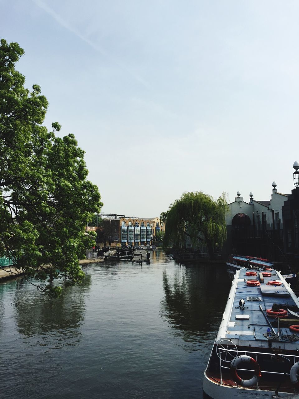 architecture, building exterior, built structure, water, tree, waterfront, clear sky, transportation, nautical vessel, river, mode of transport, canal, house, boat, sky, day, reflection, outdoors, city, residential building