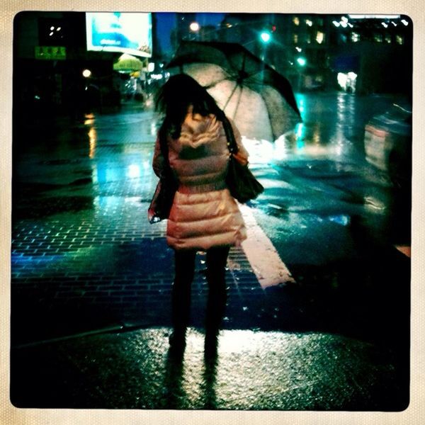 WOMAN WALKING IN ILLUMINATED CITY AT NIGHT