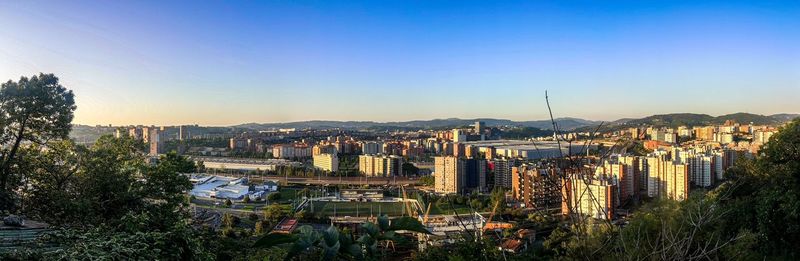 High angle view of buildings in city against clear blue sky