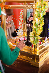 Cropped image of people pouring water on buddha statue