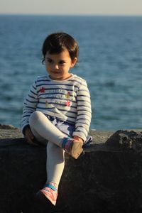 Thoughtful girl sitting on railing against sea