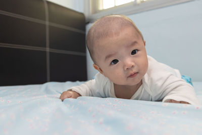 Portrait of cute baby lying on bed