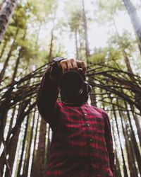 Low angle view of man photographing in forest