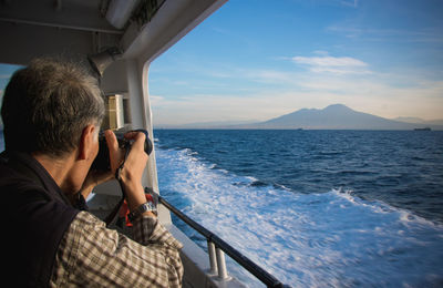 Man photographing sea against sky