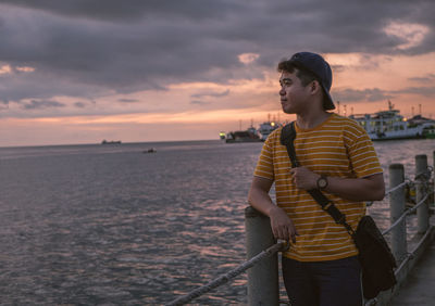 Young man looking at sea against sky