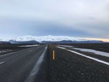 Road on snow covered landscape against sky