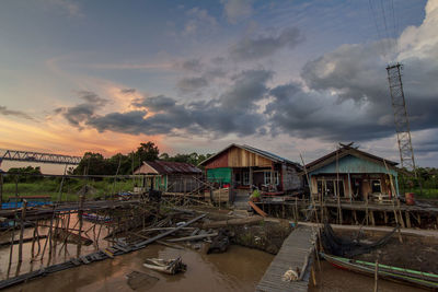 High angle view of houses by river against sky during sunset